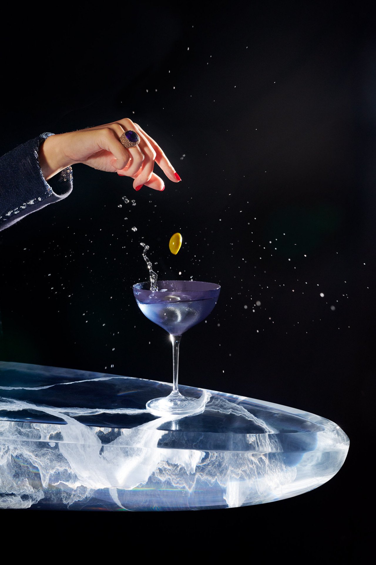cocktail dry martini sur fond noir avec une main faisant tomber des olives