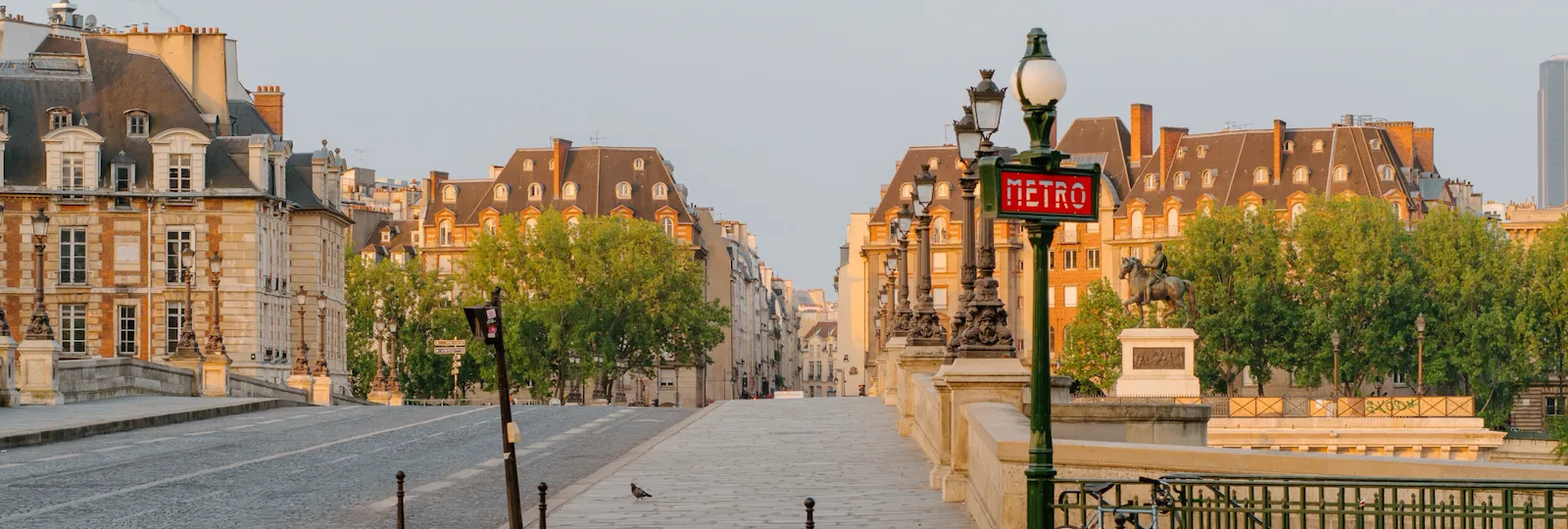 Vue de dessus du pont, avec la route qui passe sur elle, avec un signe de métro et des bâtiments orangés à l’arrière