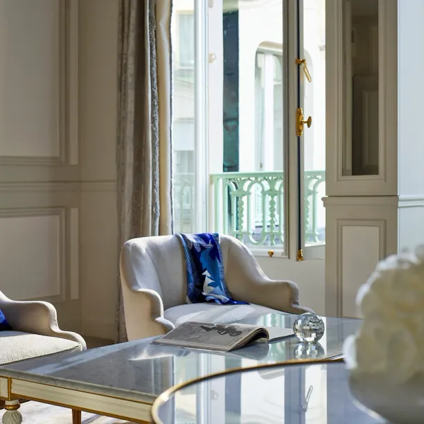Sala de estar de uma suite de luxo com destaque para a janela aberta no Le Meurice, Paris.