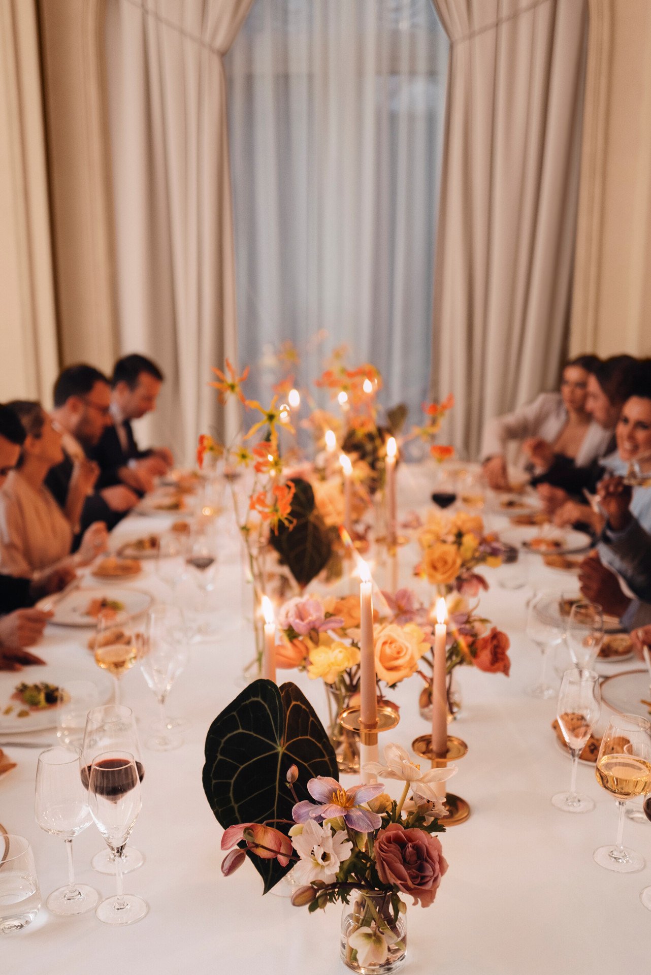 Cena con persone sedute intorno ad un tavolo imbandito. grande finestra sullo sfondo