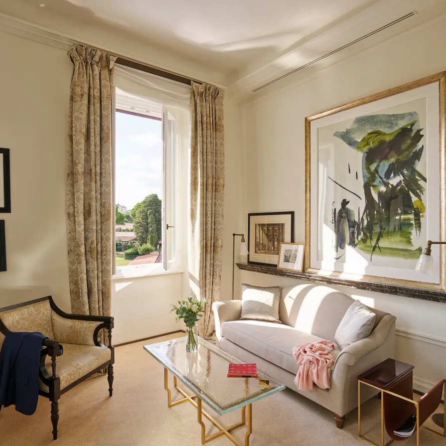 Living room with couch, armchair, paintings and coffee table at Classic Suite with view at Hotel Eden, Rome