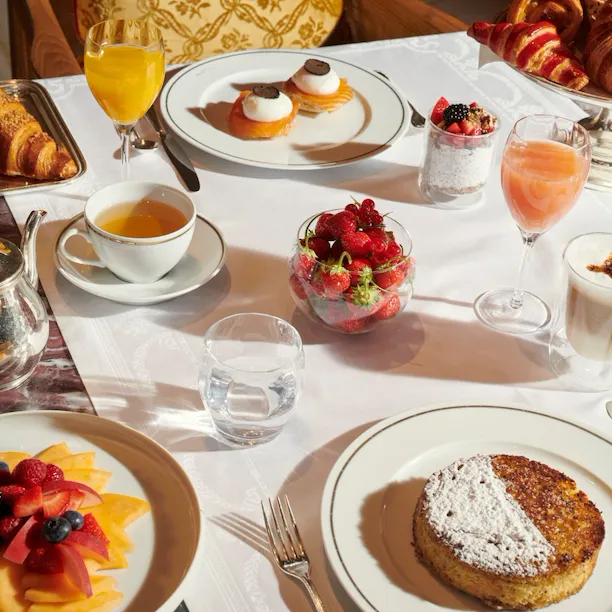 Imagens do brunch no quarto Imagens do brunch no Jean Imbert au Plaza Athénée. Podemos ver uma salada de frutas, bolos, café, ovos e sucos
