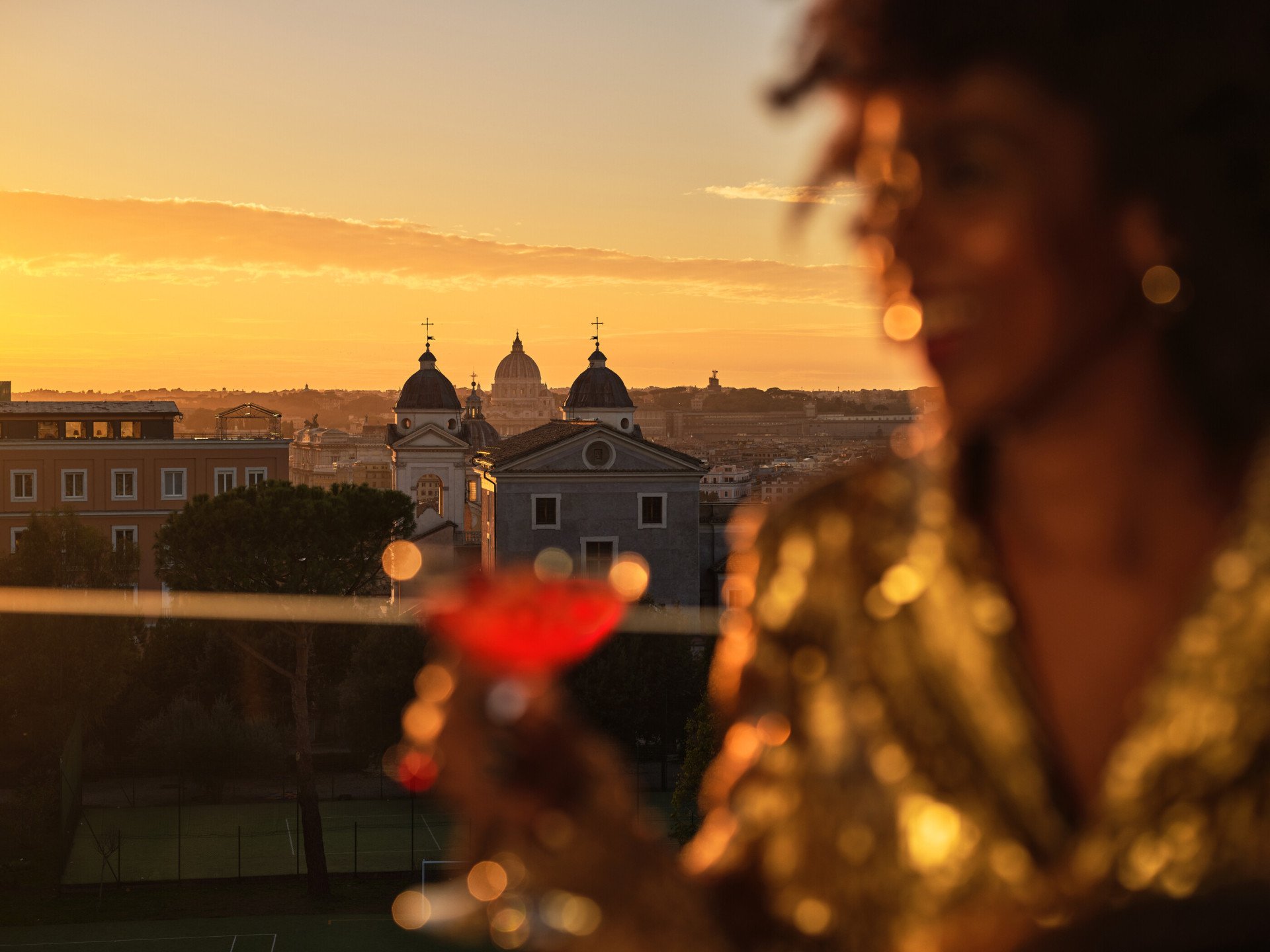 Giovane donna con cocktail a Il Giardino Bar con sfondo di vista di Roma