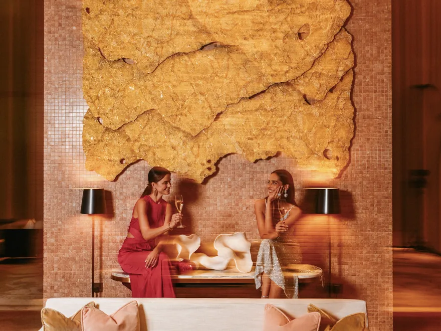 Two ladies enjoying their drinks in front of the Honeycomb art piece at The Gallery.
