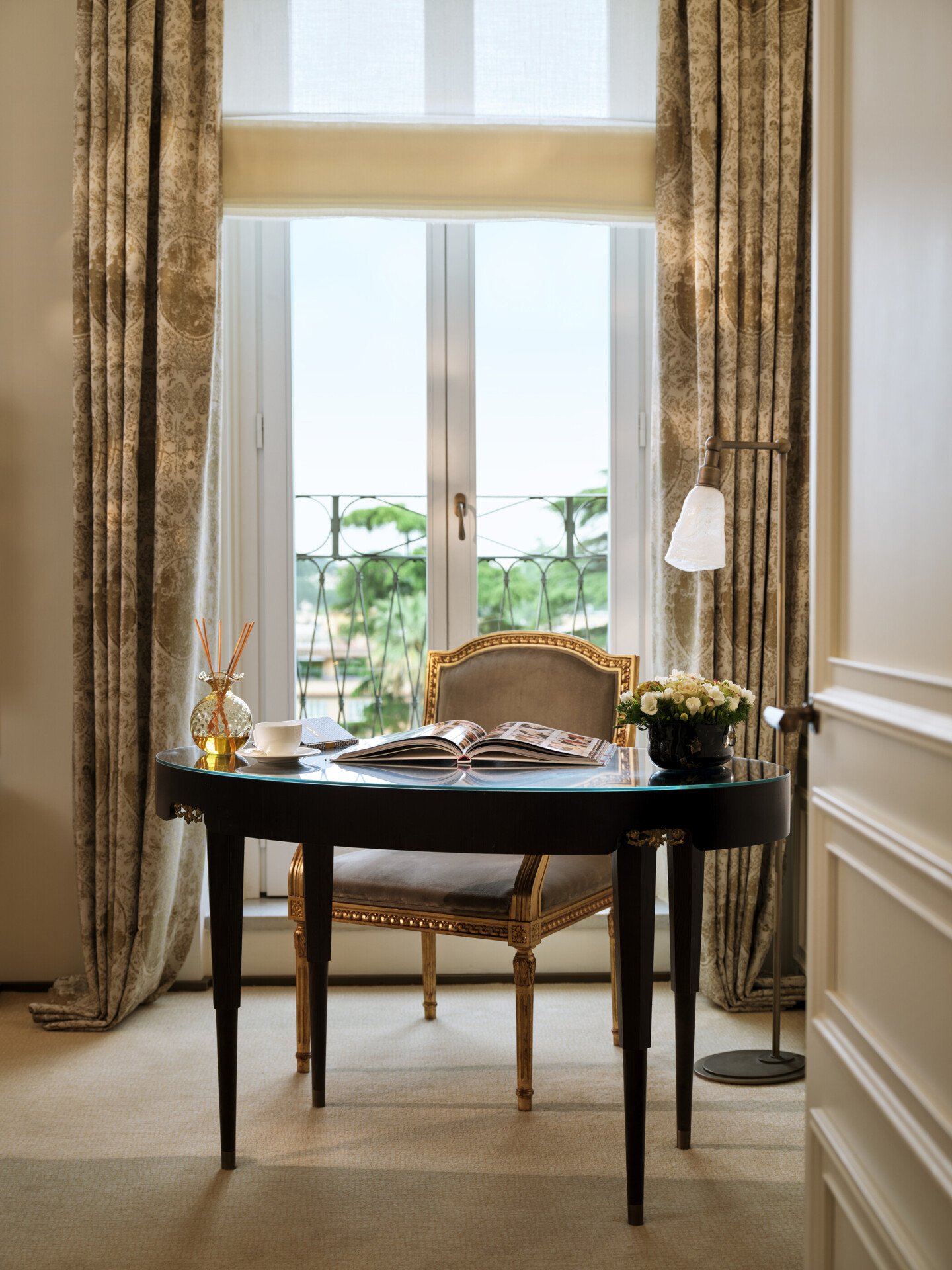 Scrivania con libro aperto e tazza di caffè davanti la porta-finestra della Grande Bellezza Suite a Hotel Eden Roma