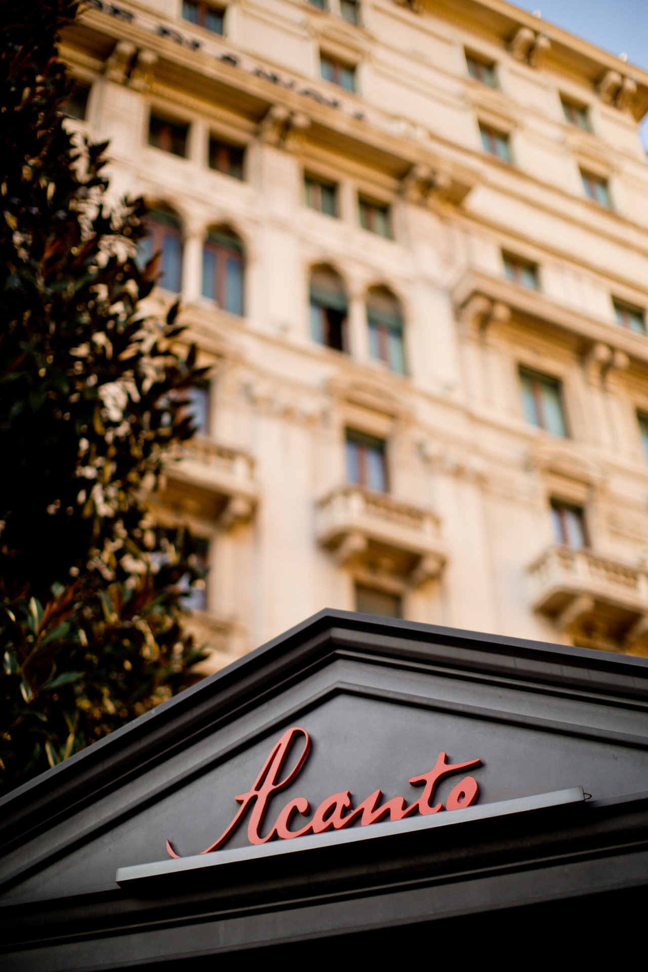 Un primo piano dell'insegna del nostro ristorante Acanto, con la facciata neoclassica sullo sfondo.