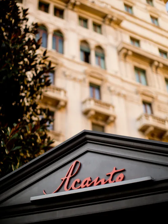 Un primo piano dell'insegna del nostro ristorante Acanto, con la facciata neoclassica sullo sfondo.