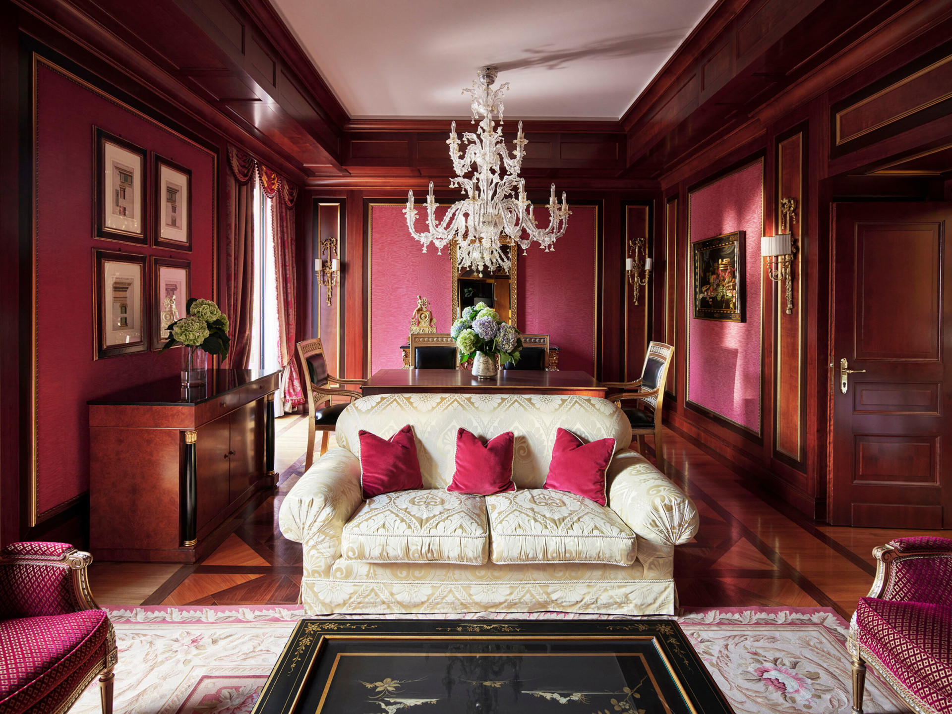 Panoramica del soggiorno della Royal Suite con un arredamento prevalentemente rosso e un divano bianco in primo piano.