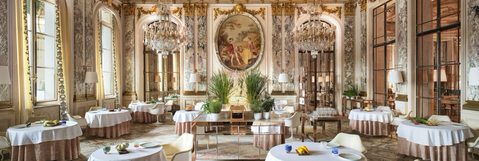Large view of Le Restaurant le Meurice Alain Ducasse with the furnitures, the chandeliers, the plants and the food on the tables, at Le Meurice, Paris