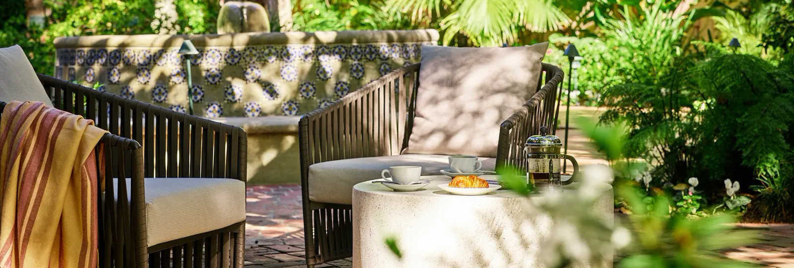 Garden chair in the gardens of Hotel Bel-Air with dappled sunlight, Los Angeles
