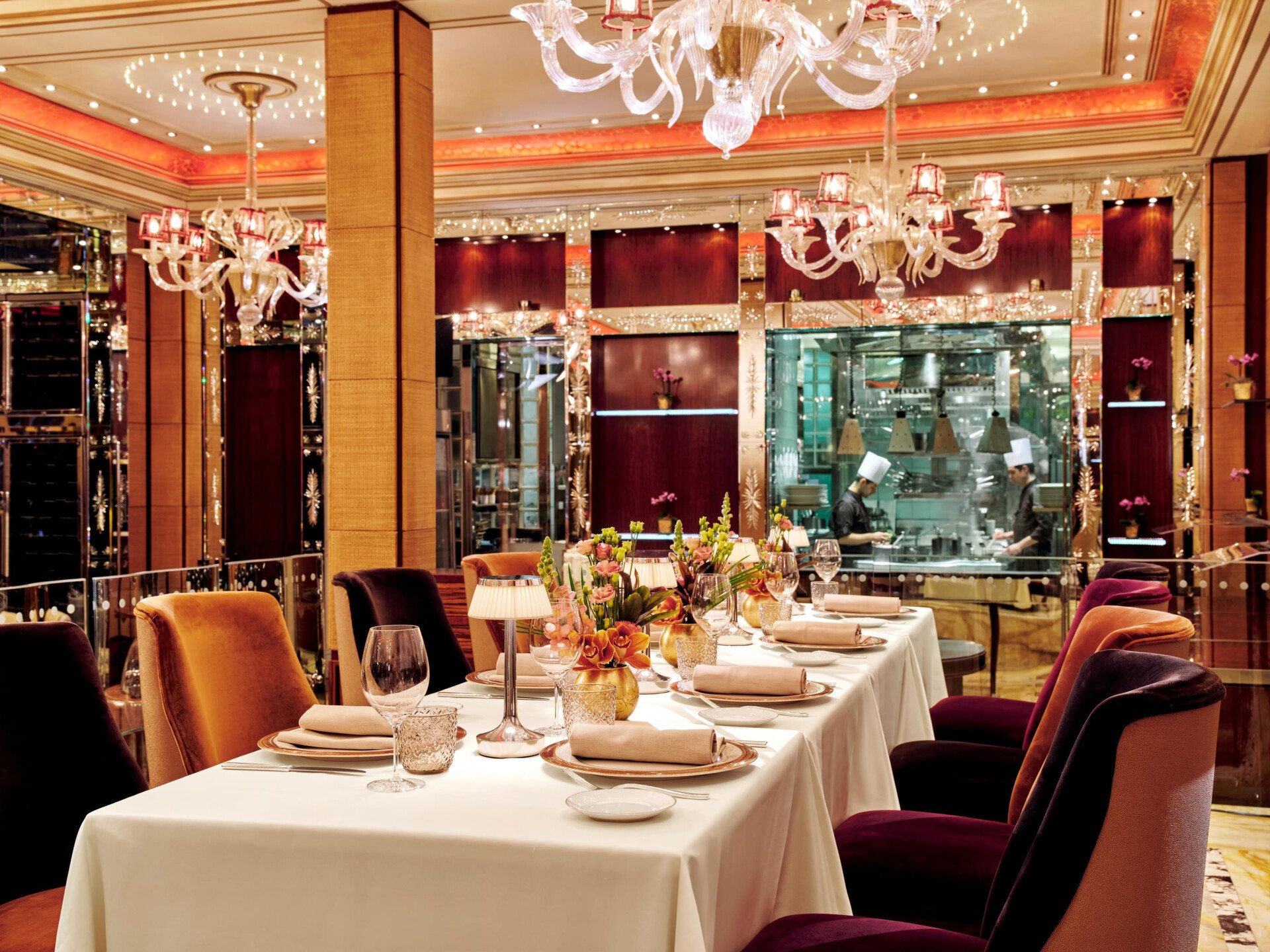 Tavolo imbandito al ristorante Acanto in primo piano. Cucina a vista sullo sfondo.