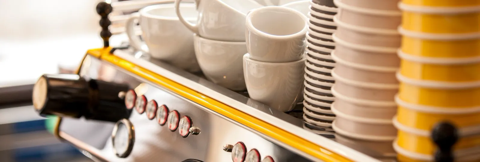 Close-up of the coffee station at Parcafé at The Dorchester, showcasing an espresso machine topped with neatly stacked cups and saucers, ready for barista-crafted drinks.
