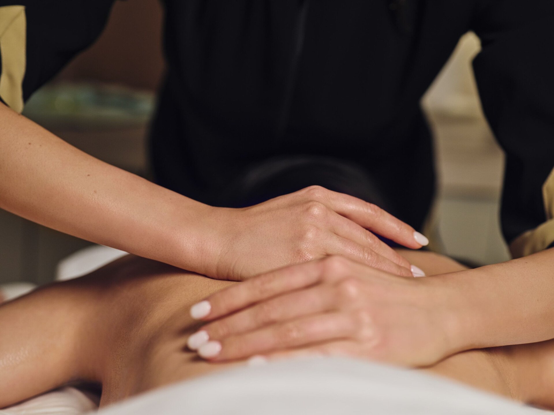 Spa therapist massaging the back of a laying woman