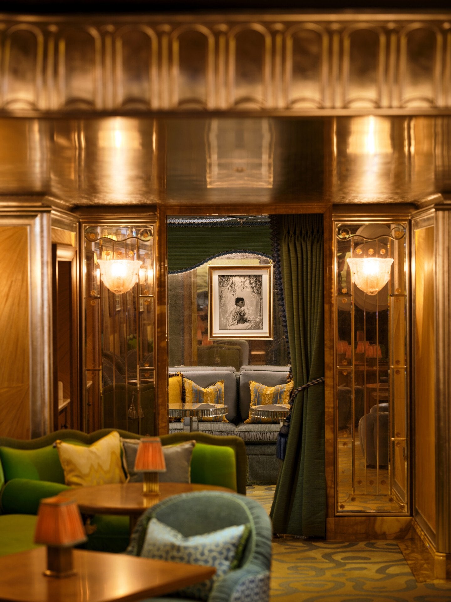 The Snug at The Vesper Bar, a secluded seating area framed by rich wood panelling, green seating and elegant draped curtains.