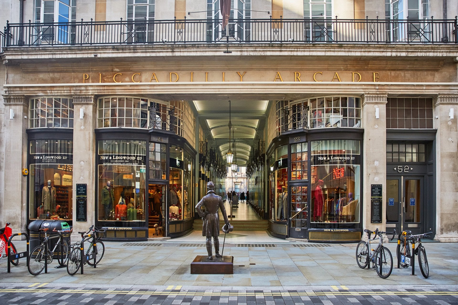 Bronze male statue with bikes either side outside Picadilly Arcade, Mayfair, London