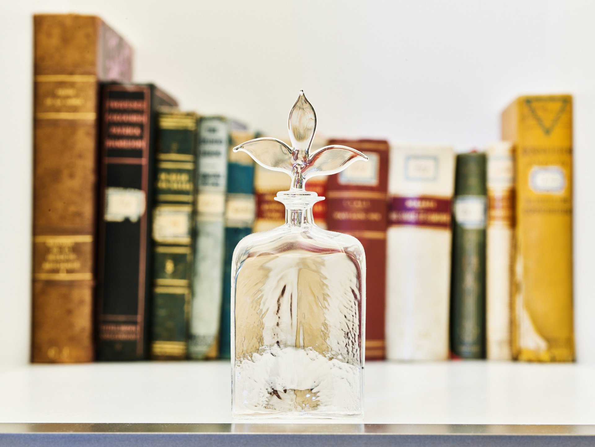 Bottiglia in vetro di Murano davanti a selezione di libri d'antiquariato in una suite di Hotel Eden Roma