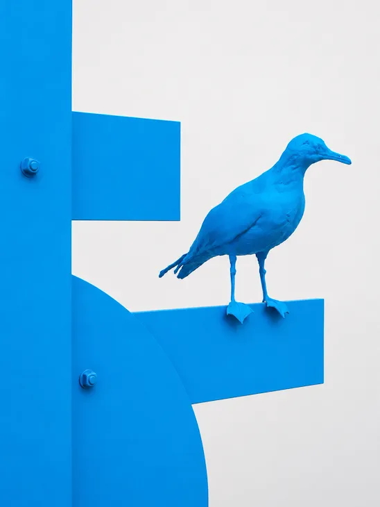 Artist, Nathan Mabry's blue sculpture of a bird perched on a structure.
