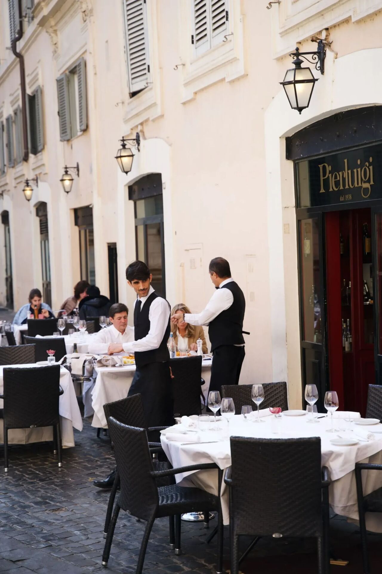 Due camerieri tra i tavoli davanti al ristorante Pierluigi a Roma