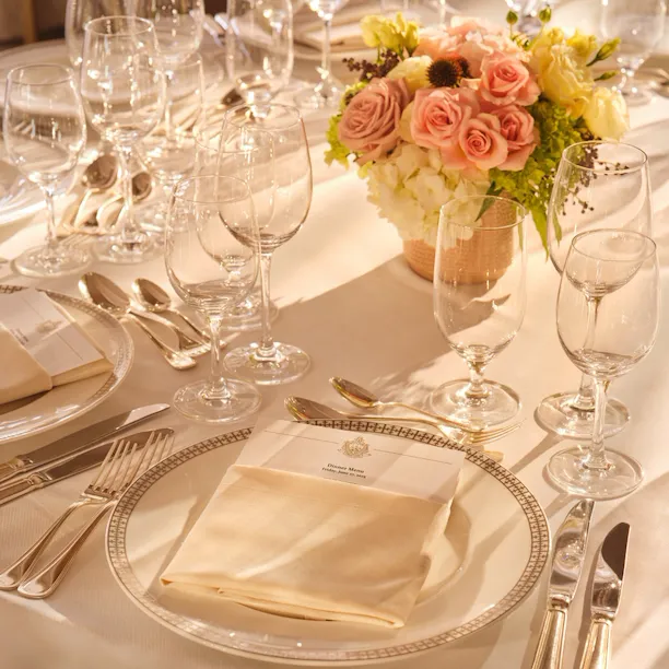 Elegant table setting with glassware, cutlery, a floral centerpiece, and folded napkins for a formal event