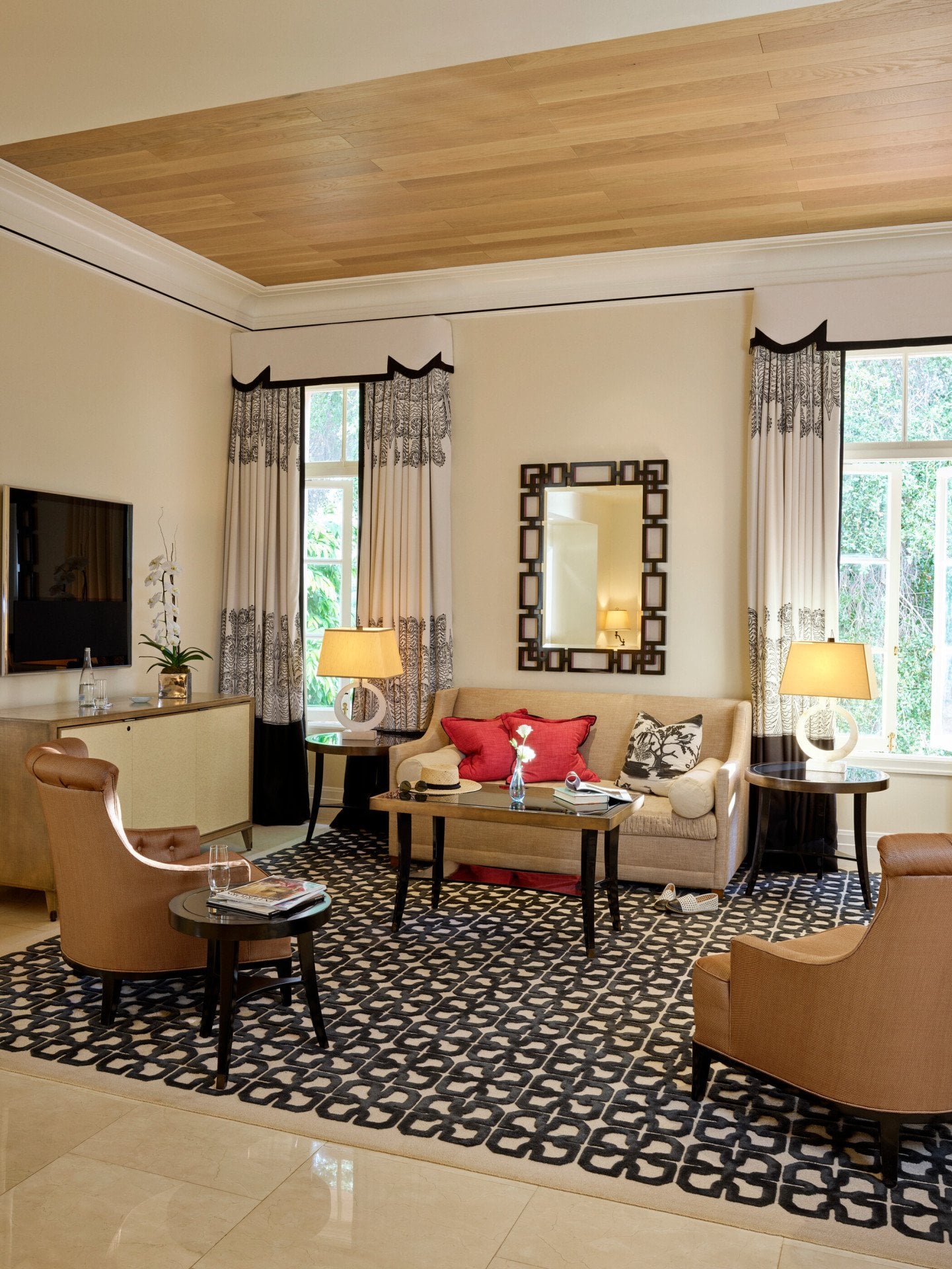 The spacious living room area of a two bedroom Bel-Air Suite featuring the coffee table, sofa, two side chairs, and TV. 