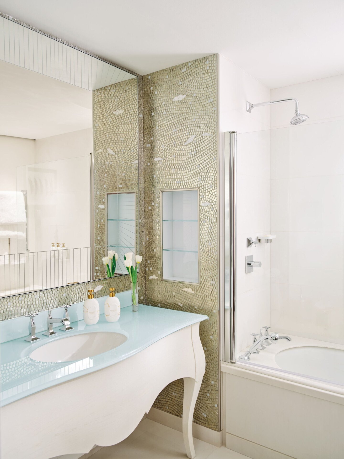 Bagno in marmo con tulipani bianchi e prodotti da bagno 