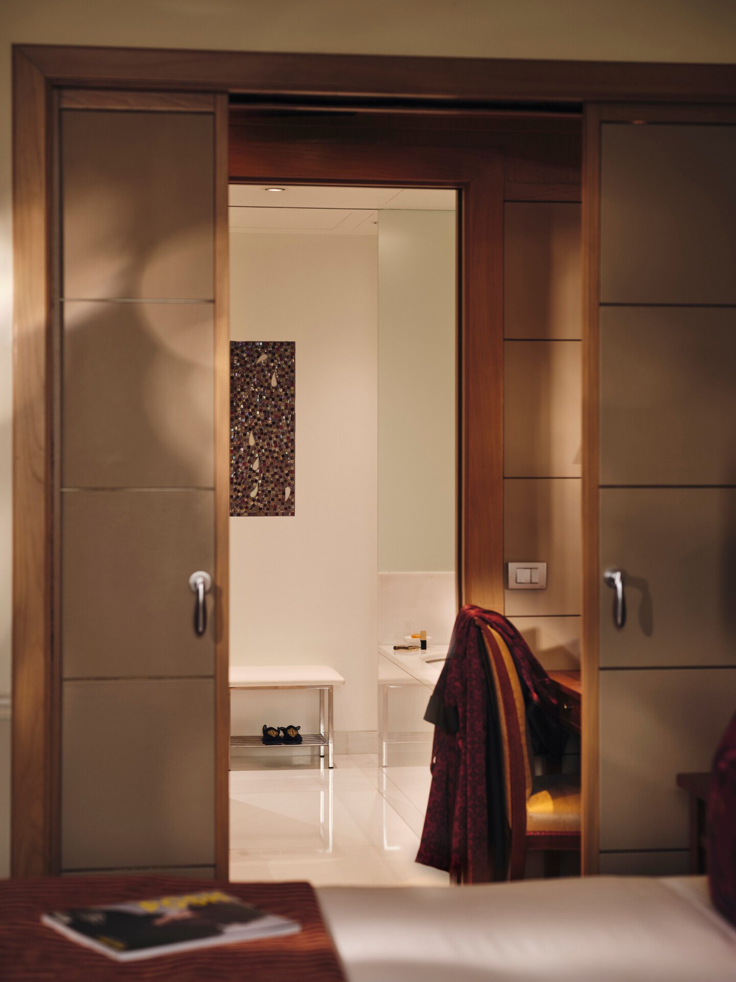 Vista del bagno dalla Camera da letto con una rivista in primo piano e una vestaglia rossa sullo sfondo