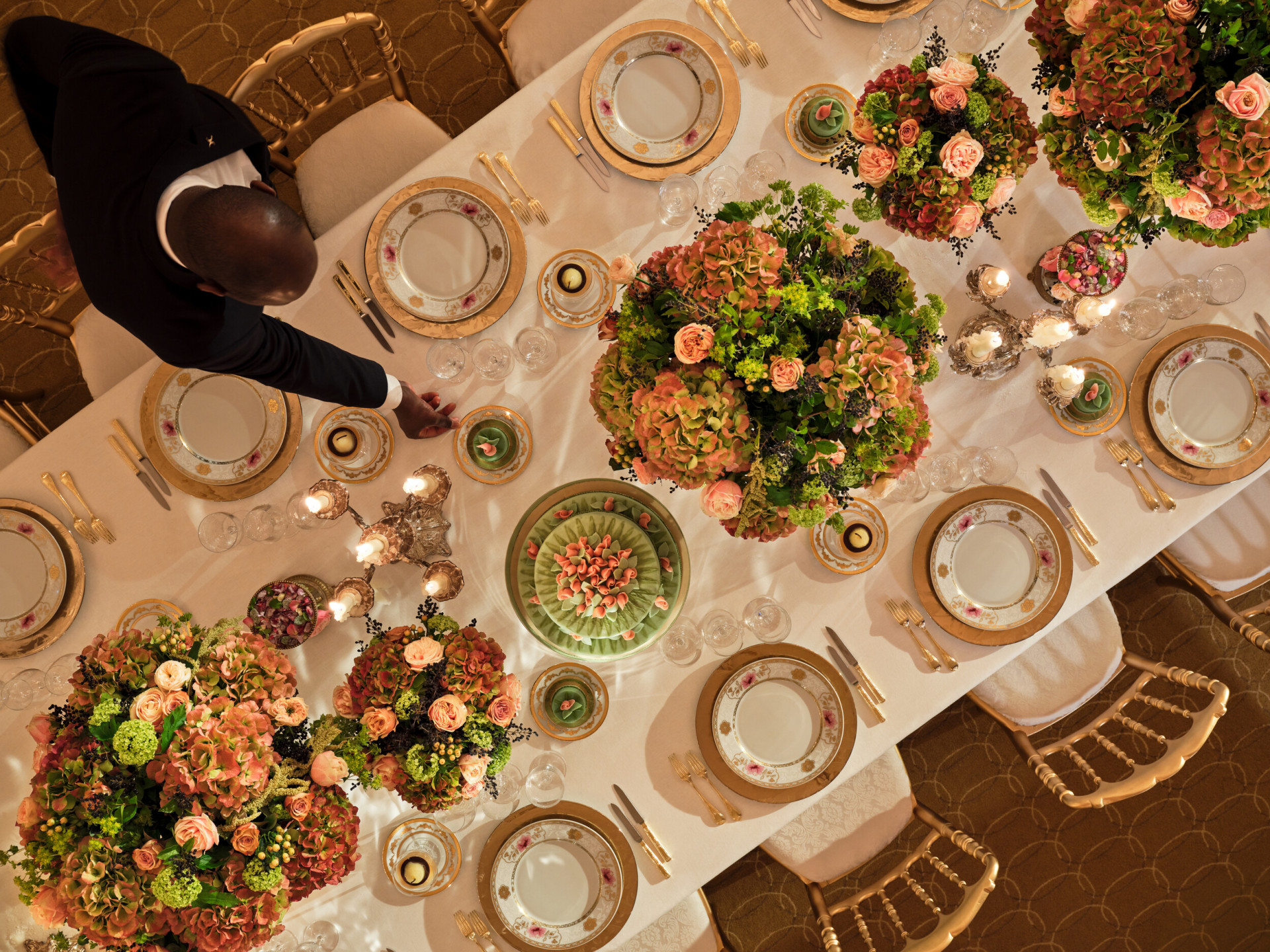 Dinner captured from the top with gold and white tableware, pink and green flowers, green cakes at Le Salon Organza, at Hôtel Plaza Athénée, Paris - Dorchester Collection.