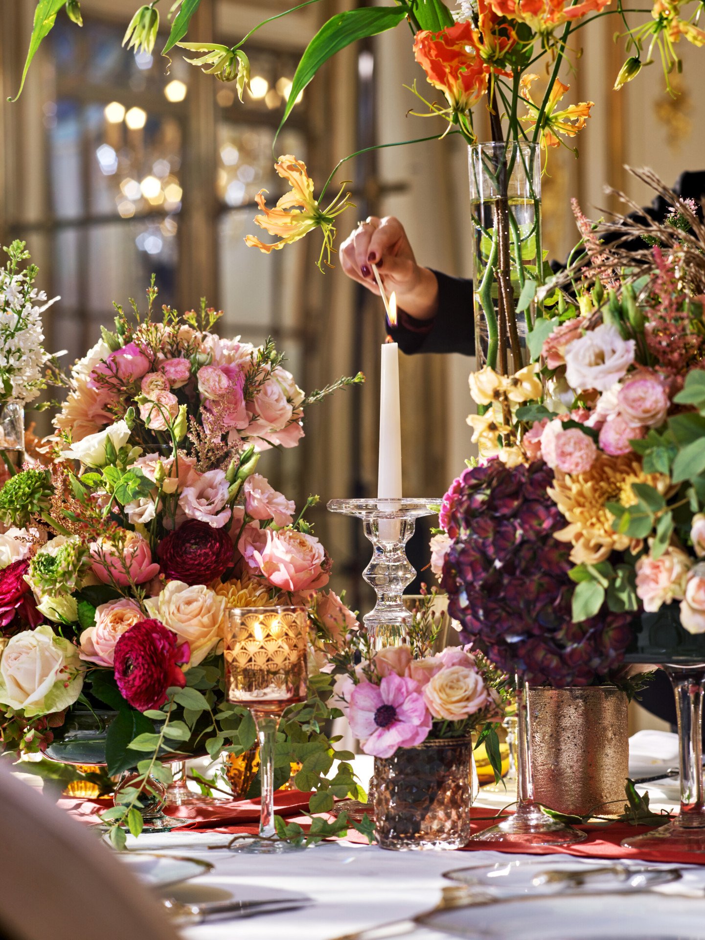 Tableware and floral detail, with an hand that lights a candlestick, in Le Salon Pompadour at Le Meurice, Paris - Dorchester Collection