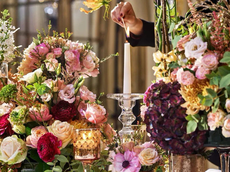 Tableware and floral detail, with an hand that lights a candlestick, in Le Salon Pompadour at Le Meurice, Paris - Dorchester Collection