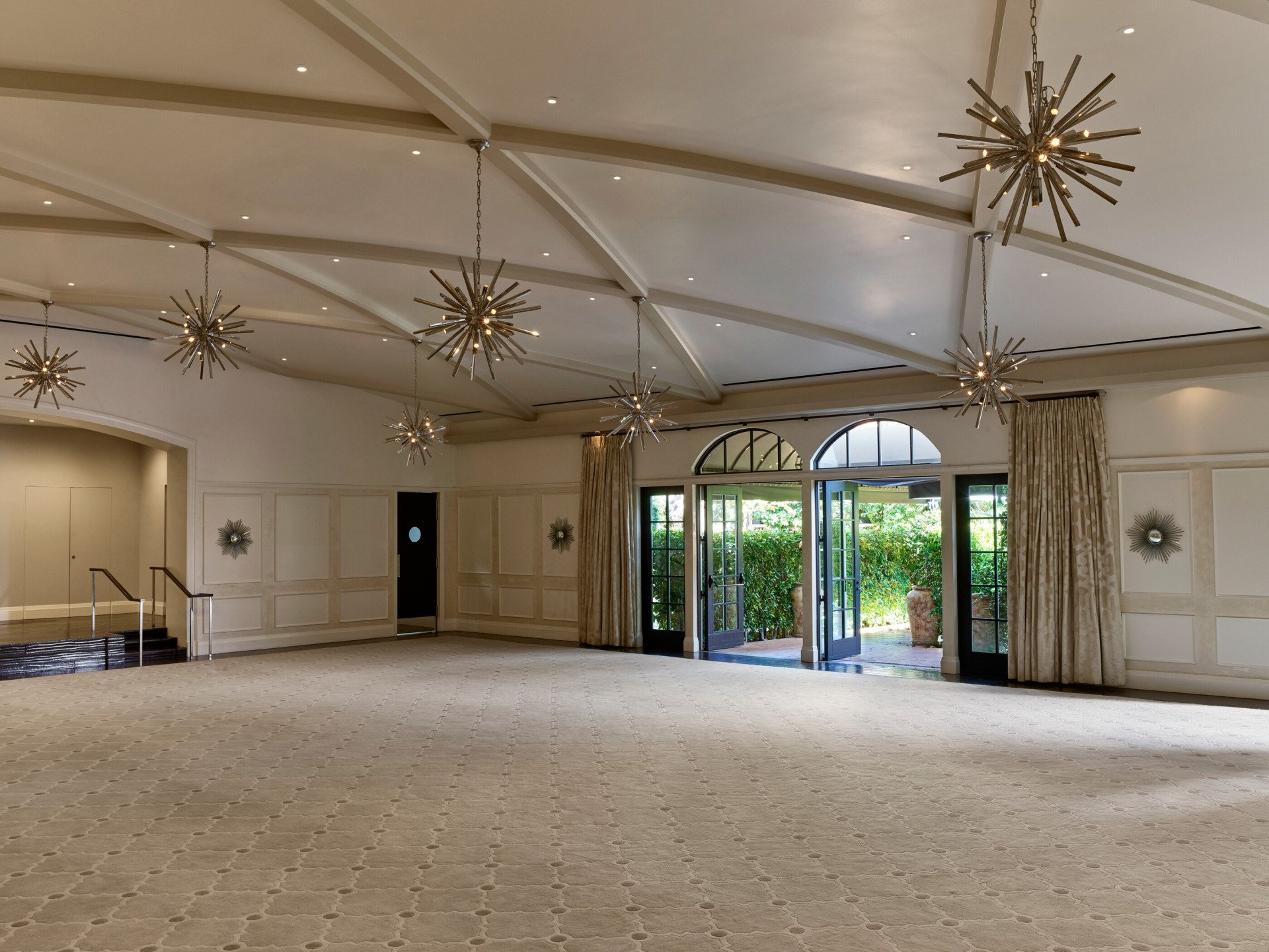 Garden Ballroom event space at Hotel Bel-Air with star-shaped chandeliers hanging and natural light from the entrance doors. 