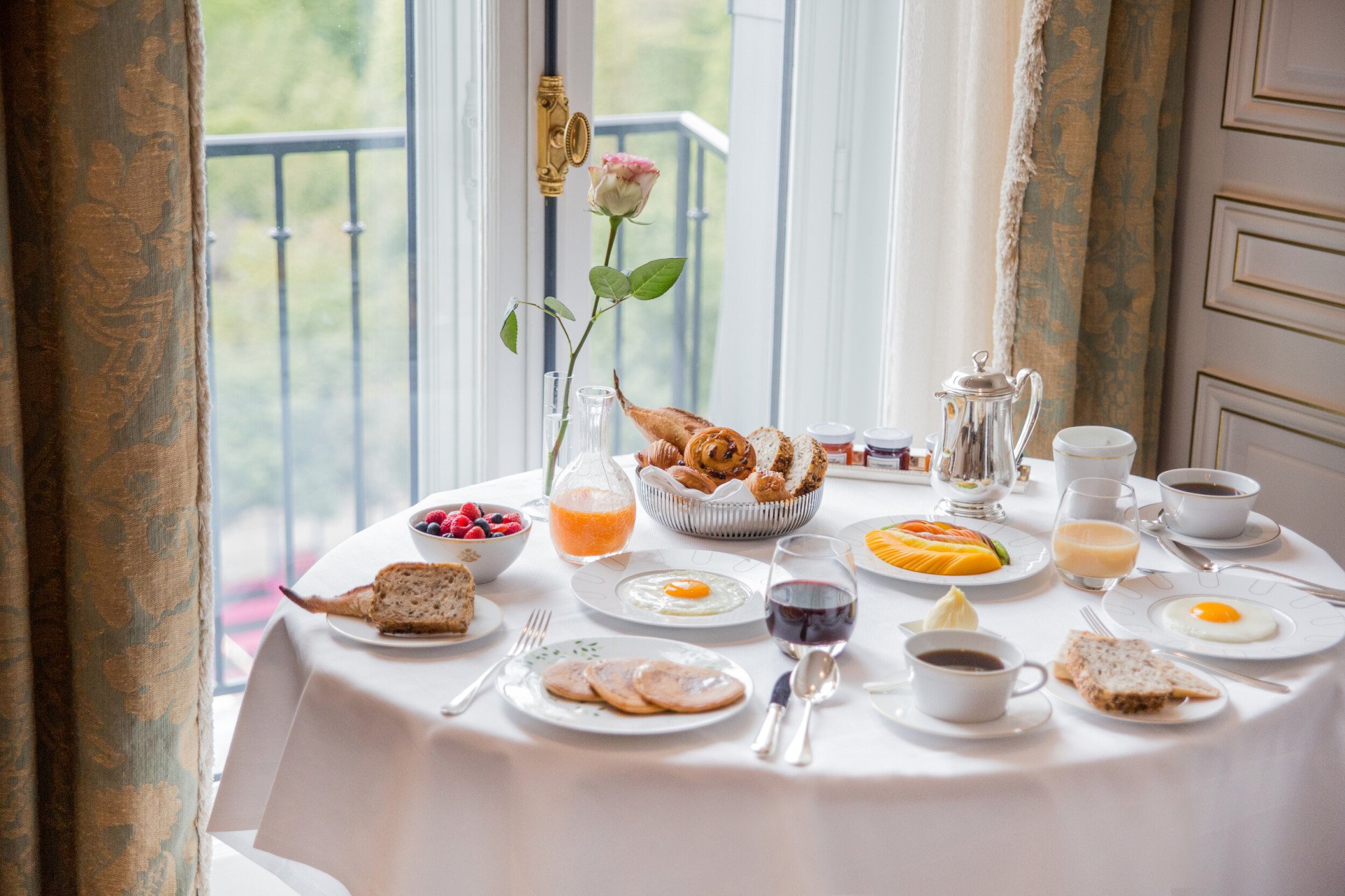 Room service table with breakfast food such as eggs, berries, fruit and pastry basket. At Le Meurice, Paris.