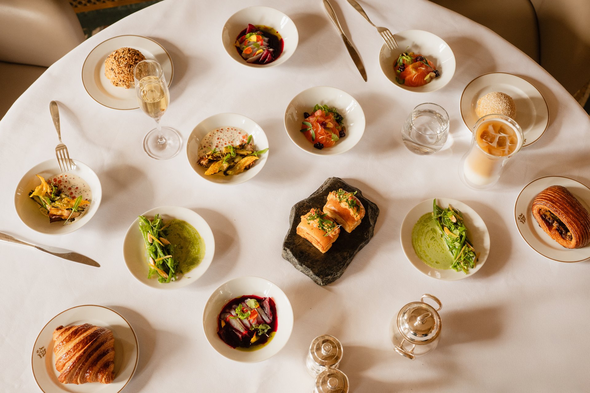 This visual shows the brunch menu of restaurant Le Meurice Alain Ducasse.  There are several sweet and savory dishes on a white table cloth.