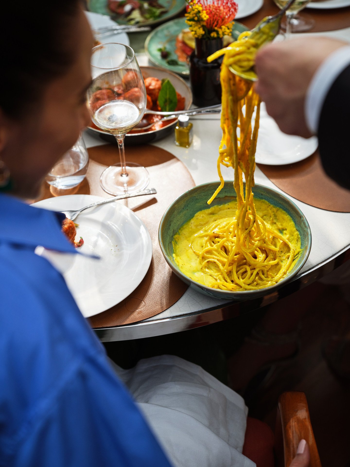 Cameriere che serve spaghetti a una donna seduta seduta ad un tavolo de Il Giardino Ristorante a Hotel Eden Roma