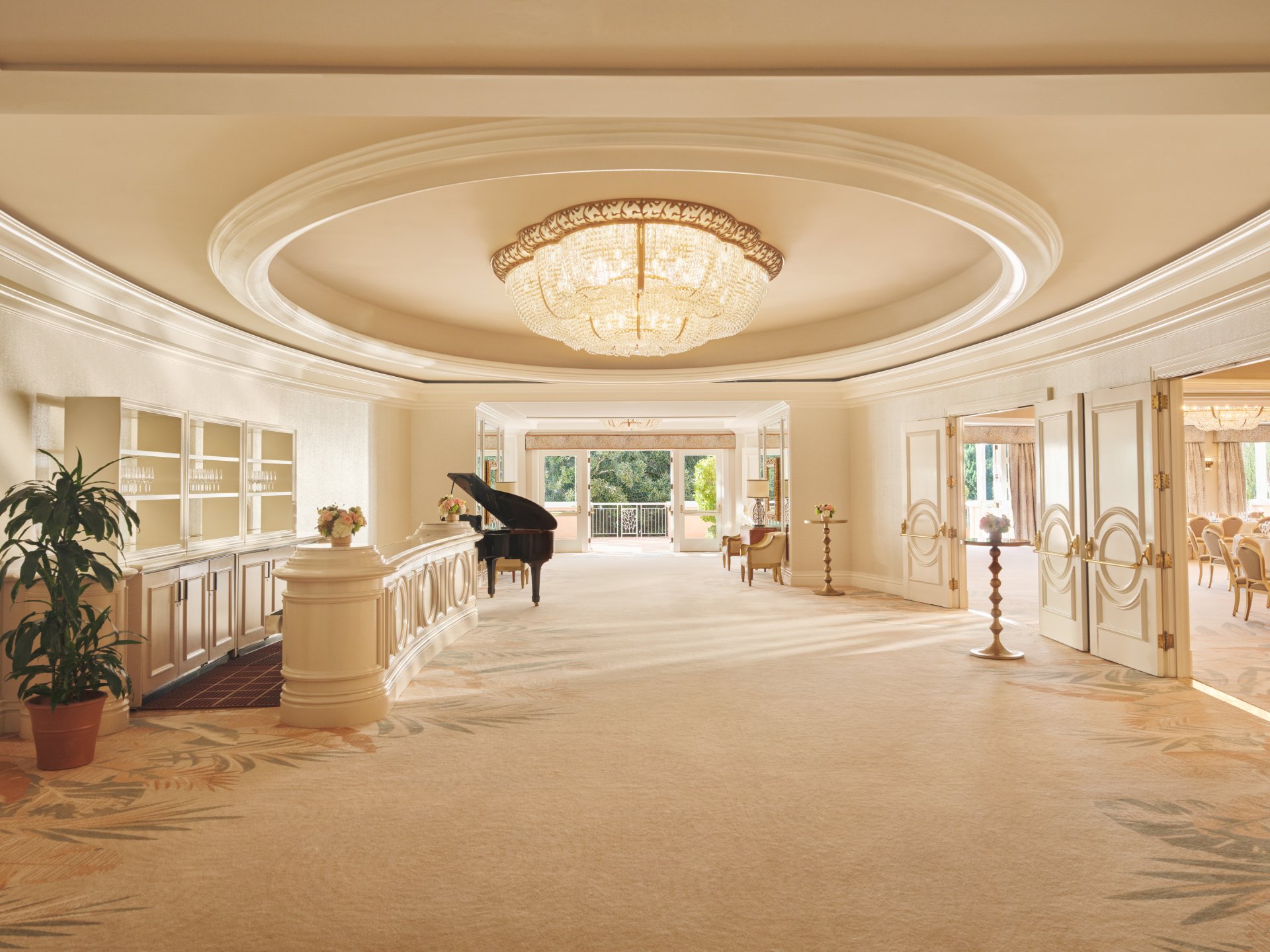 Elegant hotel lobby with grand chandelier, piano, and inviting seating area.