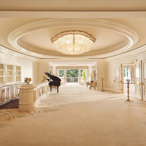 Elegant hotel lobby with grand chandelier, piano, and inviting seating area.