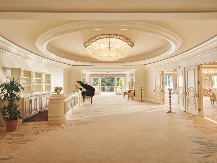 Elegant hotel lobby with grand chandelier, piano, and inviting seating area.