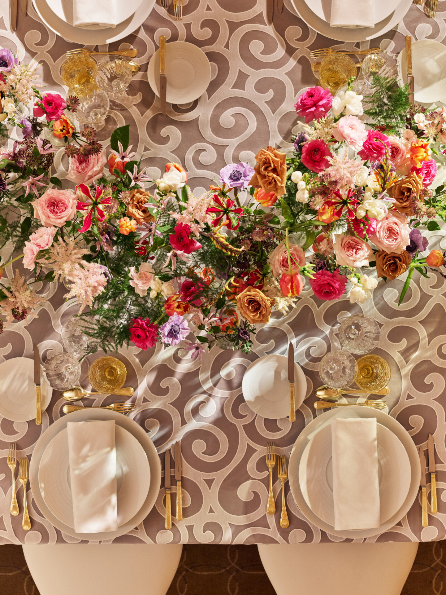 Table captured from the top with white plates, grey tablecloth, and colorful flower arrangement at Le Salon Organza, Hôtel Plaza Athénée, Paris - Dorchester Collection.