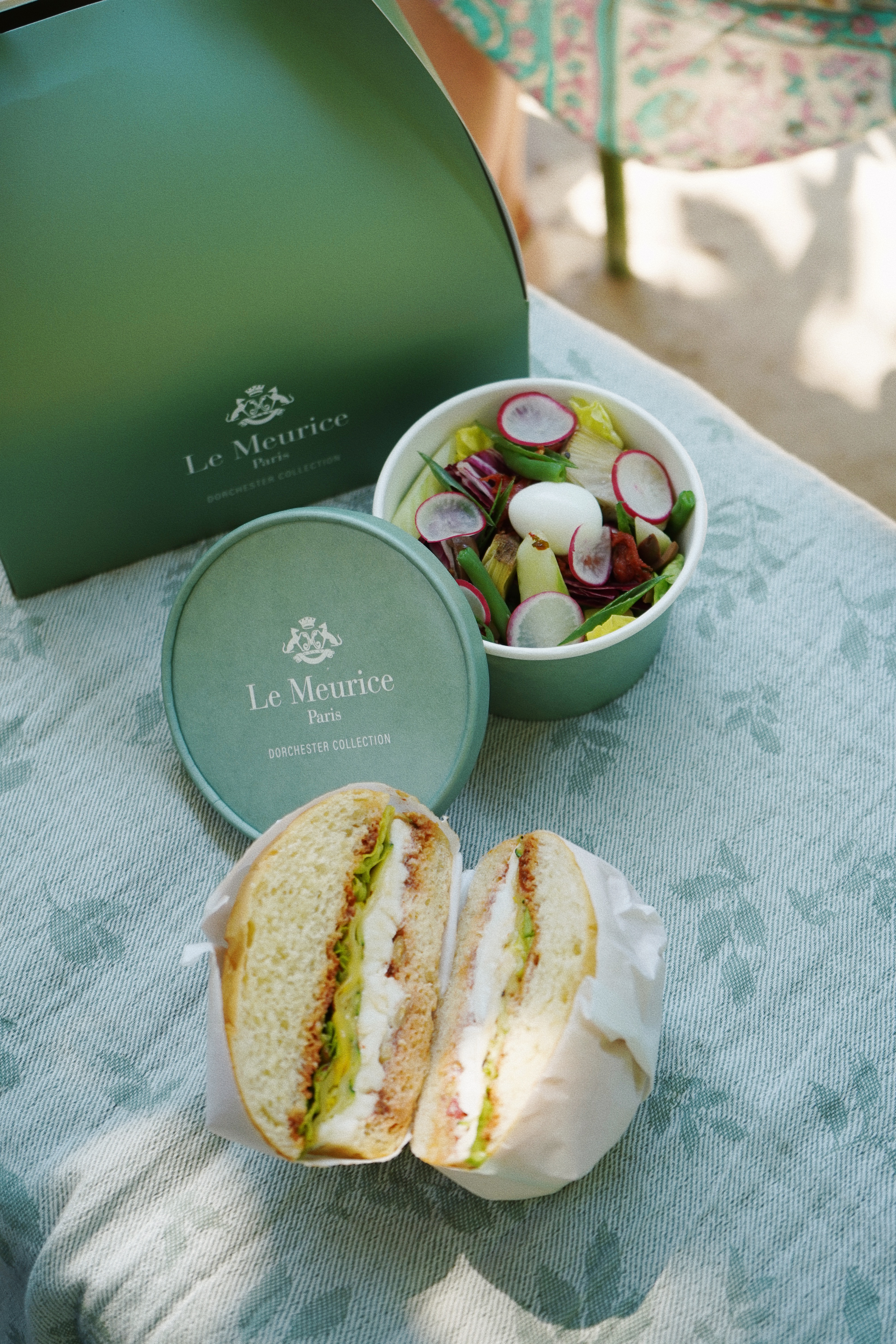 Le Meurice lunchbox, a bun and a salad displayed on a napkin.