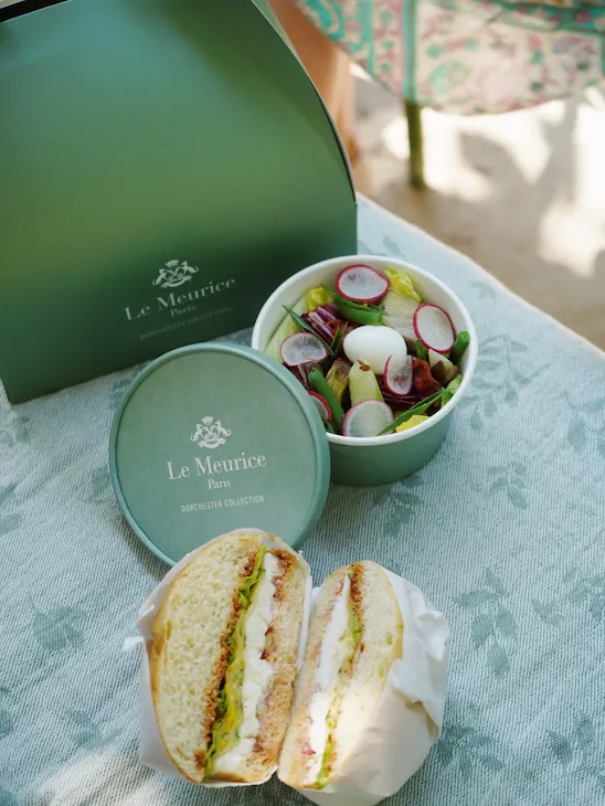 Le Meurice lunchbox, a bun and a salad displayed on a napkin.