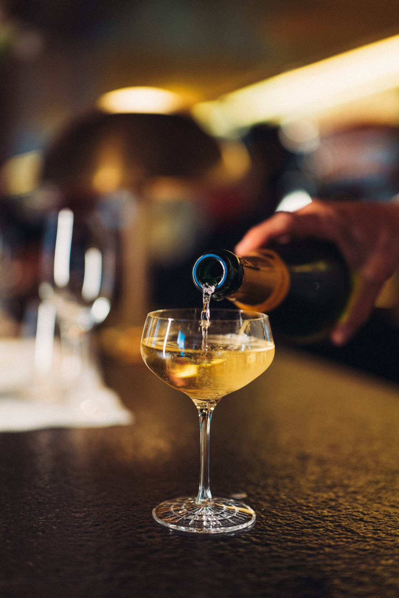 Waiter pouring a glass of champaign on the bar counter of Le Relais Plaza, at Hotel Plaza Athénée, Paris