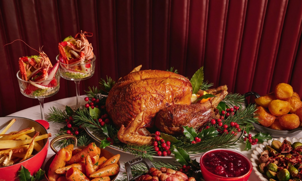 Festive Christmas dining at The Grill at The Dorchester, showcasing a traditional roast turkey served with all the trimmings, alongside prawn cocktail, roast potatoes, glazed carrots, Brussels sprouts and cranberry sauce.