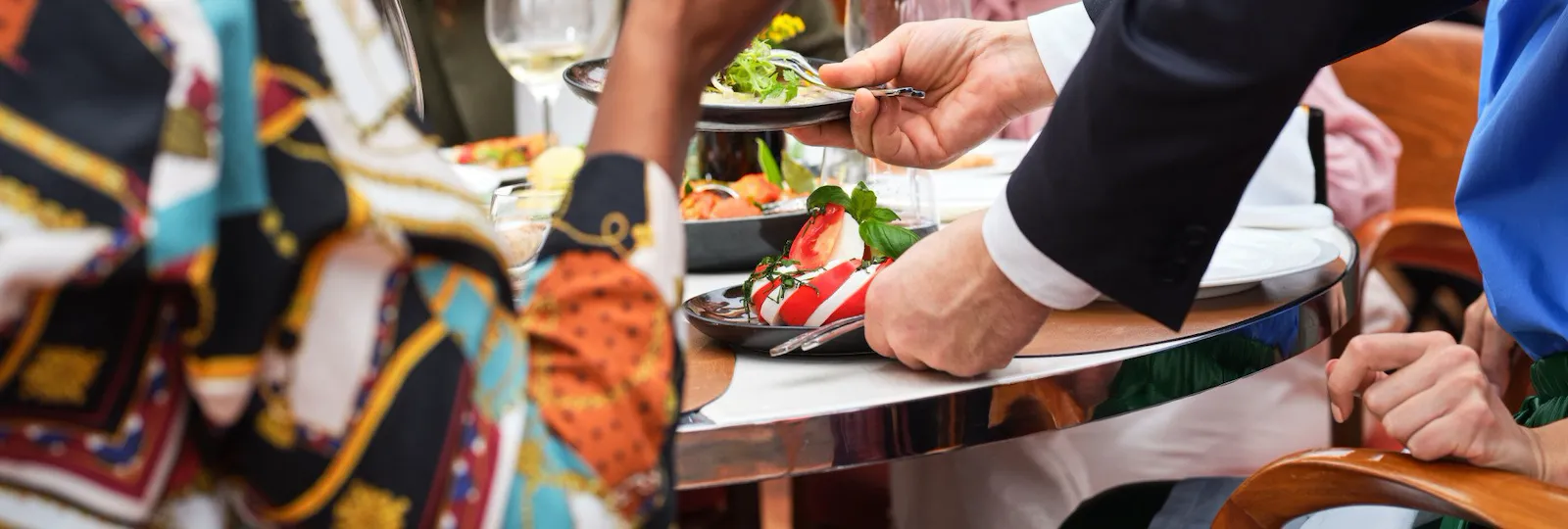 Primo piano sul tavolo composto da amici che brindano al ristorante Il Giardino, Hotel Eden