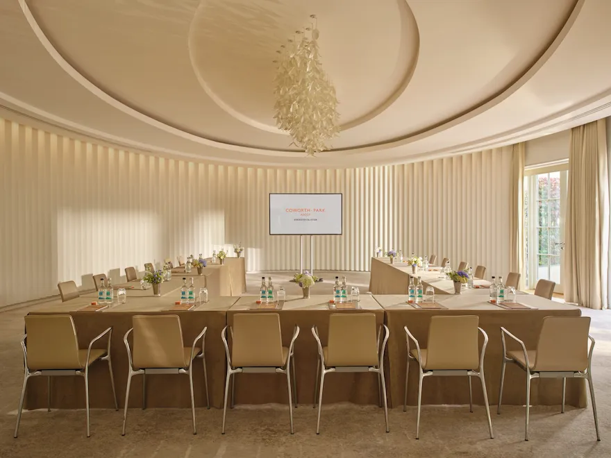 Oval room set up in boardroom style with presentation screen at Coworth Park, Ascot