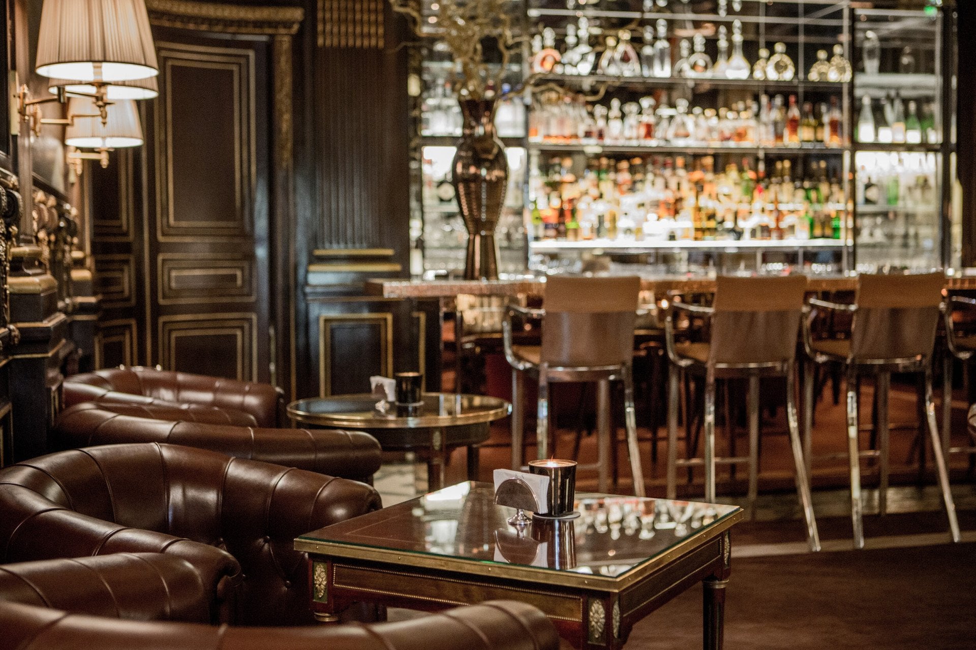 Low tables in the forefront and the glass bar shelves blurred out in the back, at Le Meurice, Paris.


