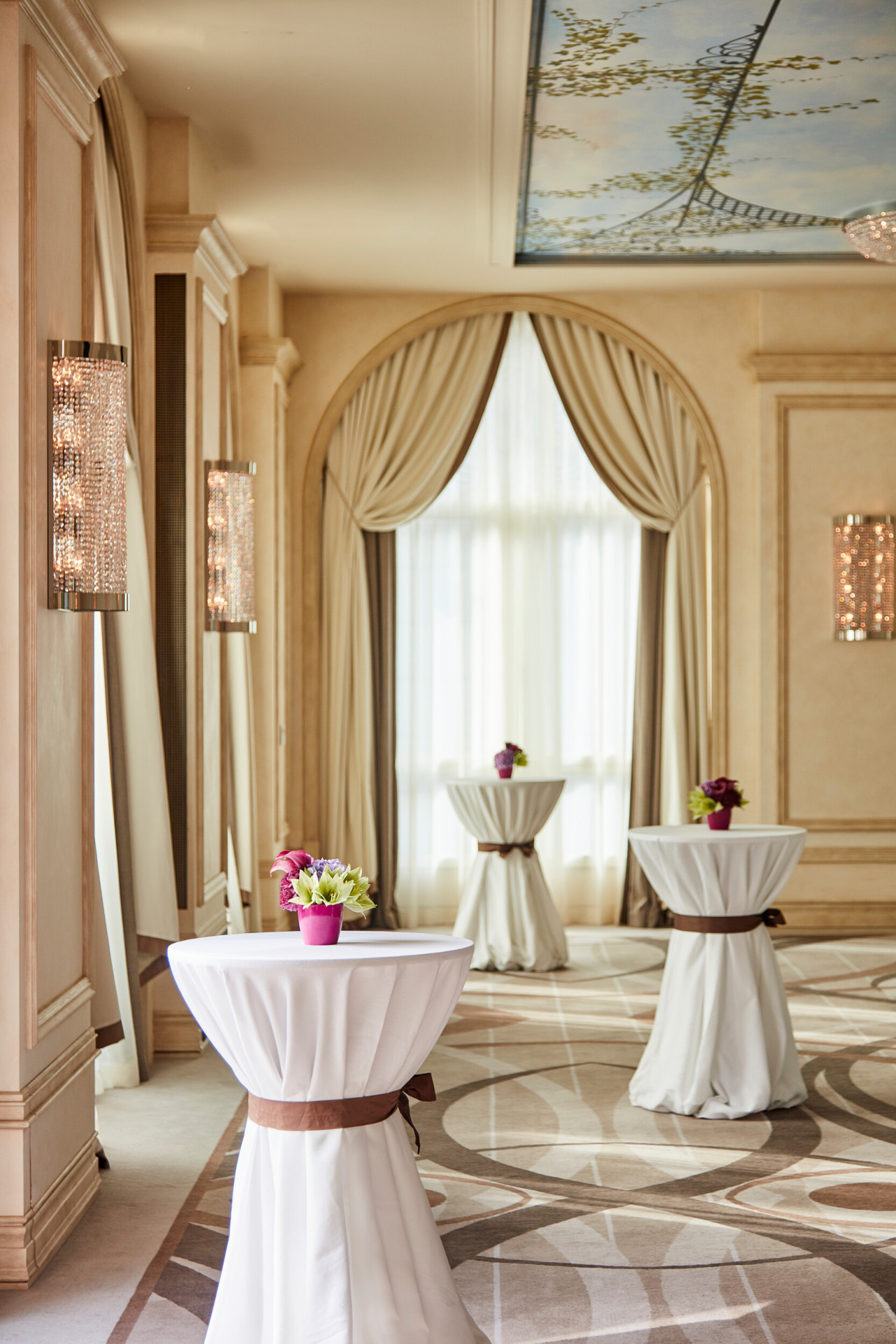 tre tavoli da cocktail in sala veranda con centrotavola di fiori rosa e verdi 