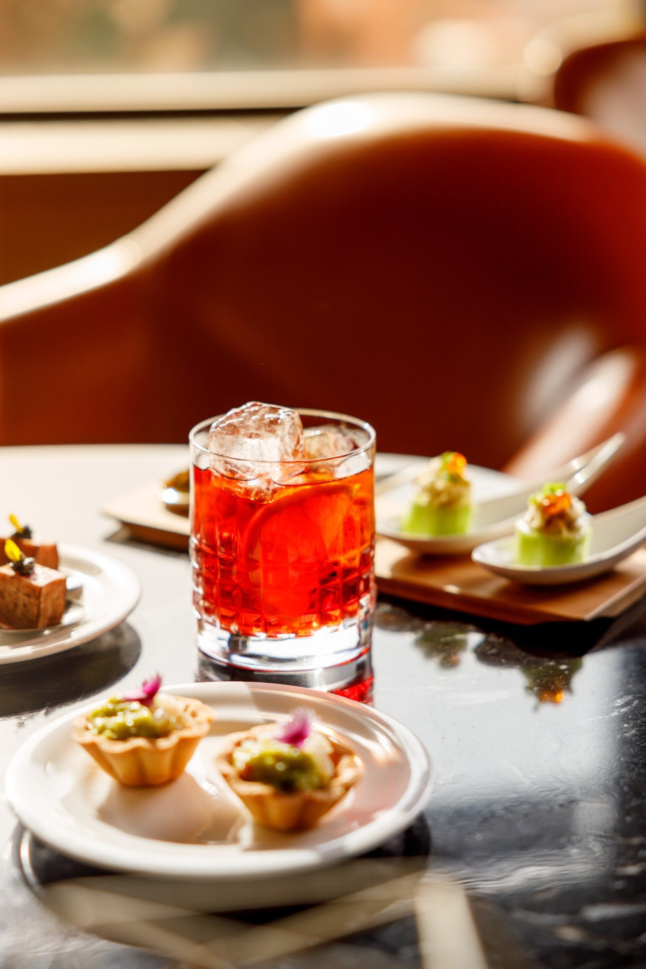 Bicchiere di negroni e selezione di tartine da aperitivo su un tavolo a Il Giardino Bar