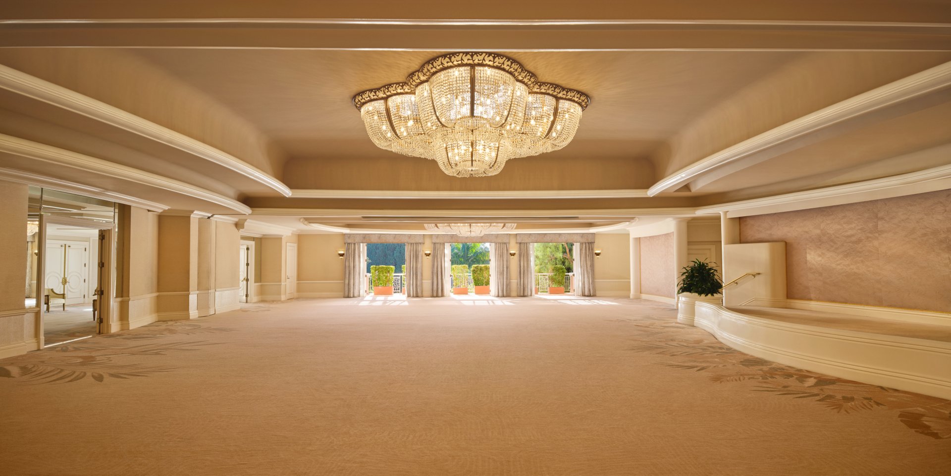 Elegant, empty banquet hall with chandelier and large windows, calm and grand setting
