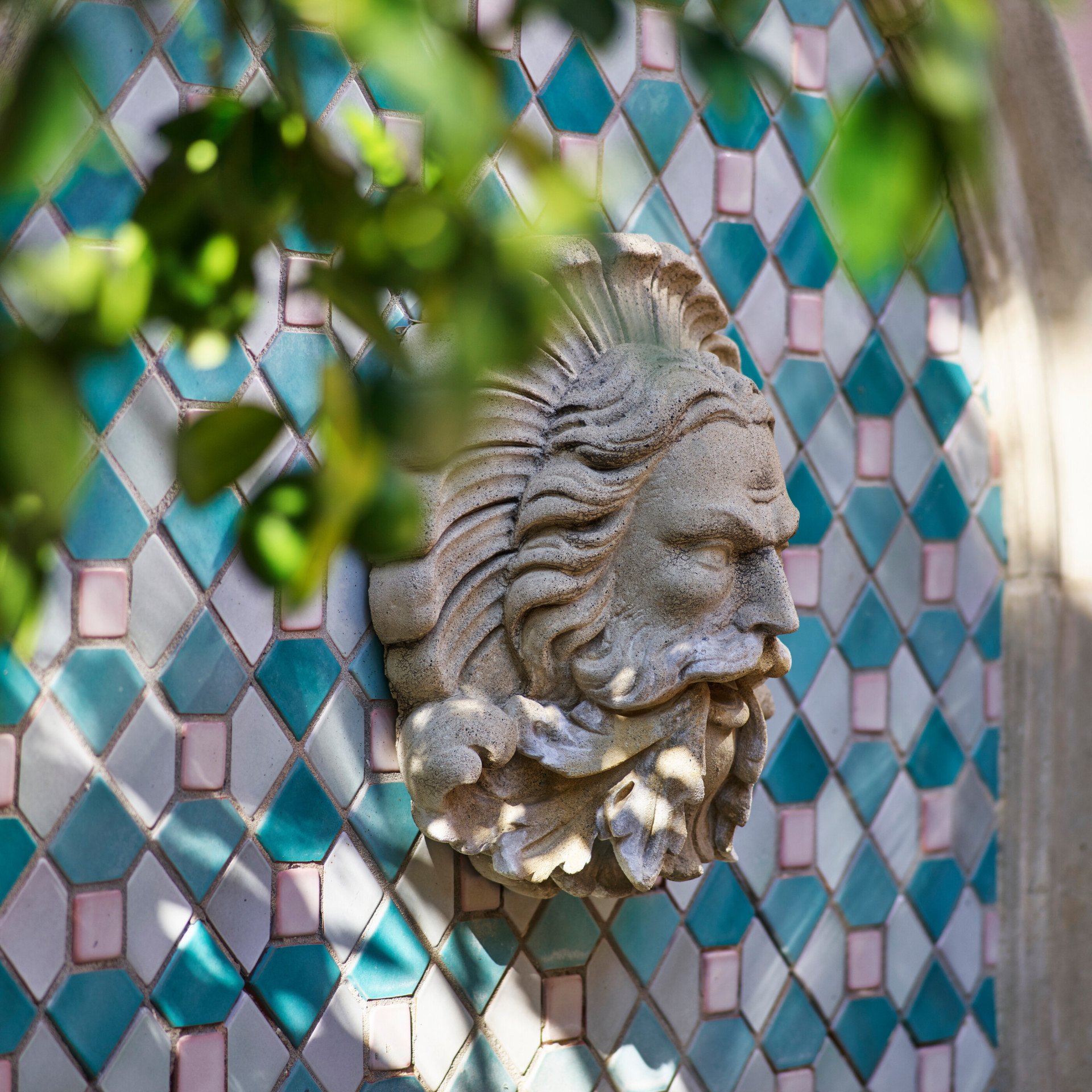 Stone face in center with blue and white mosaic tiles on fountain at Hotel Bel-Air