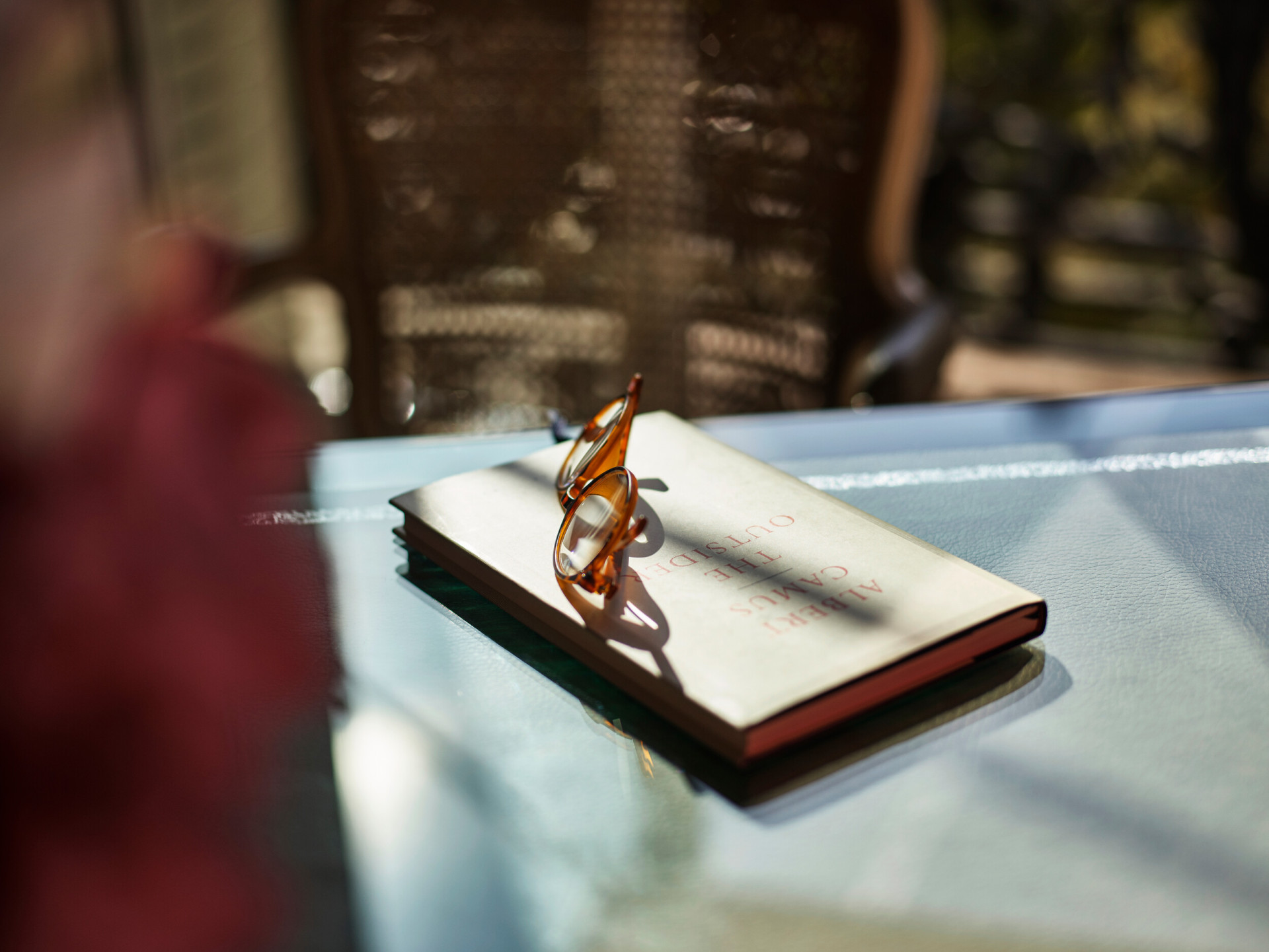 A book and a glass on a table with a sunlit background