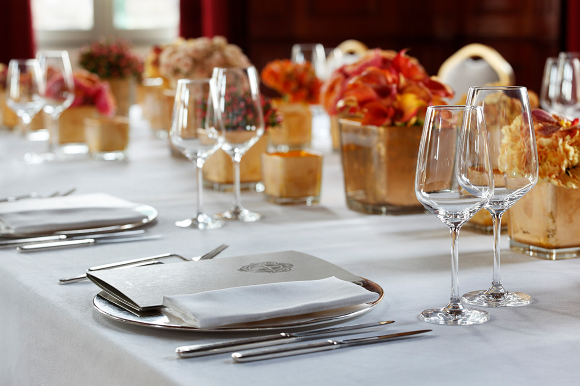A close-up of a table laid for dinner in our ‘Club Principe’ events space. The table features several centrepieces with flowers in shades of orange.